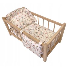    Un letto per bambole in legno con delicata biancheria da letto a motivi floreali